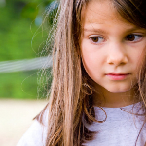 brunette child in white shirt looking away from camera
