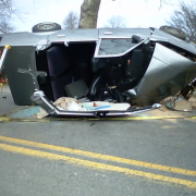 silver car flipped over with roof torn off