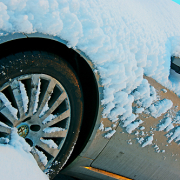 silver car completely covered in snow except tire