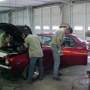 shop mechanics working on red mustange